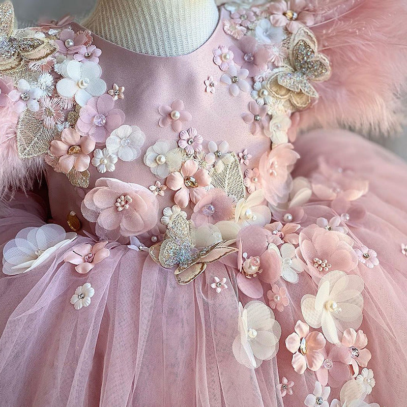 Close-up of floral appliqué, feathers, and butterfly accents on pink girls princess dress – beekaaboo.com