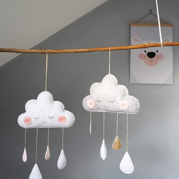 White and grey felt cloud ornaments hanging in a softly lit bedroom – nursery-ready home decor – beekaaboo.com