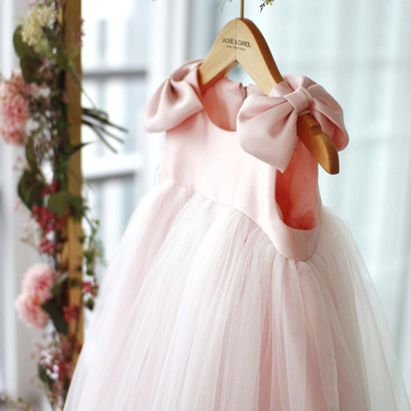 Side close-up view of baby girl pink princess dress highlighting oversized bow detail and layered skirt – beekaaboo.com
