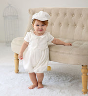 Baby wearing a white ceremony romper with matching hat from beekaaboo.com