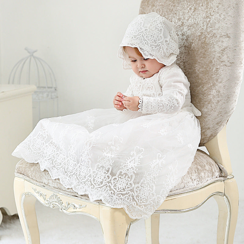 Baby wearing long sleeve baptism dress and bonnet, seated and smiling – beekaaboo.com