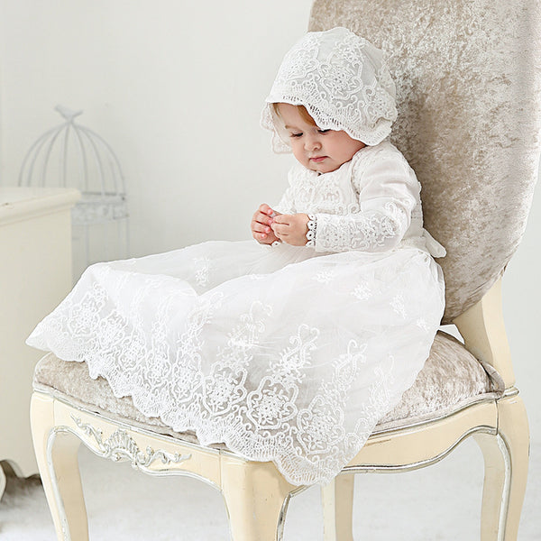 Baby wearing long sleeve baptism dress and bonnet, seated and smiling – beekaaboo.com